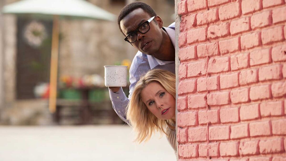 Chidi and Eleanor peek around a corner in The Good Place.