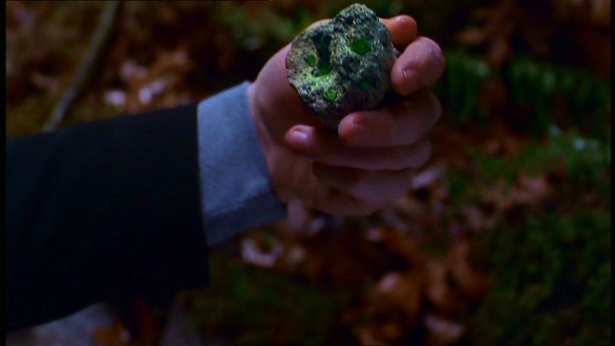 smallville hand holding a green rock of kryptonite