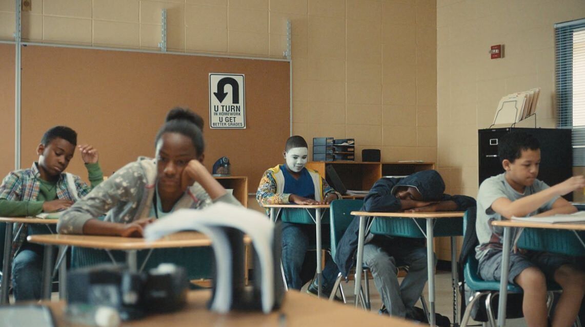 atlanta students taking a test and one kid at the back wearing a whiteface mask