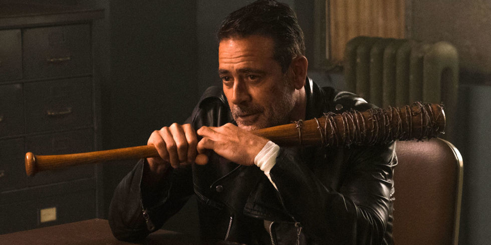 Negan sitting at a table with Lucille The Walking Dead