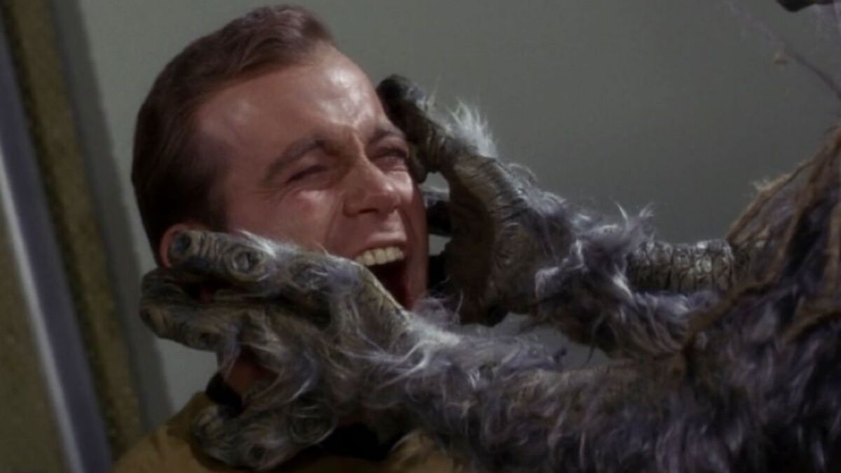 Captain Kirk screams in pain as Creature M-113 cradles his head in its hands which have suction cups to suck the salt out of an organism