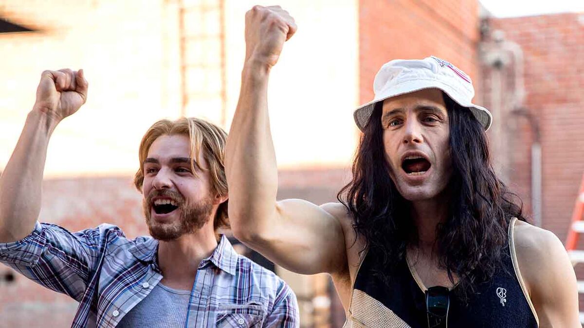 Tommy Wiseau and his friend pump fists in the air in The Disaster Artist