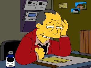 gil gunderson from The Simpsons sitting at his desk frustrated