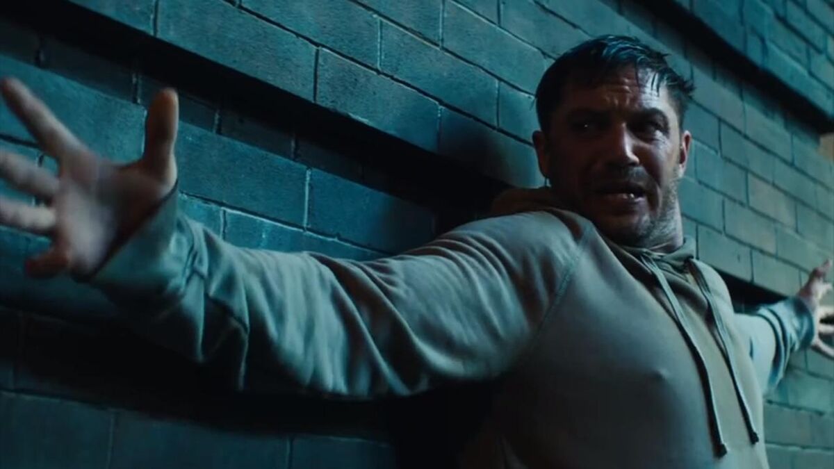 Tom Hardy, arms outstretched with a worried look on his face