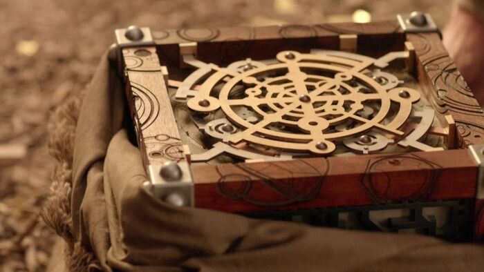 The Moment is seen here as an ornate wooden box with metal elements, seen partially obscured by a burlap sack.