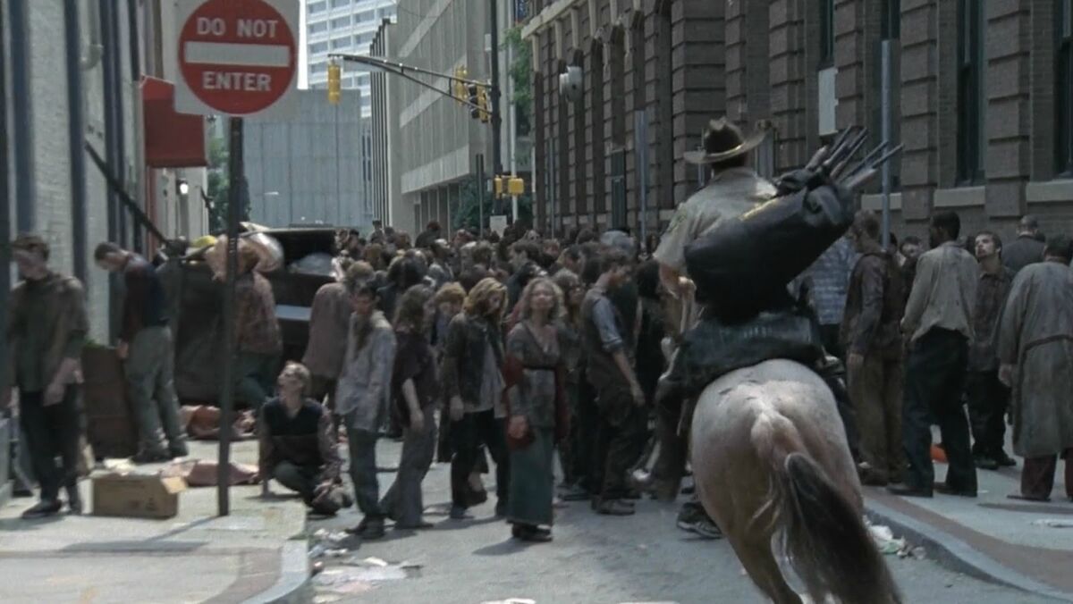 walking dead rick on horseback riding through zombie horde