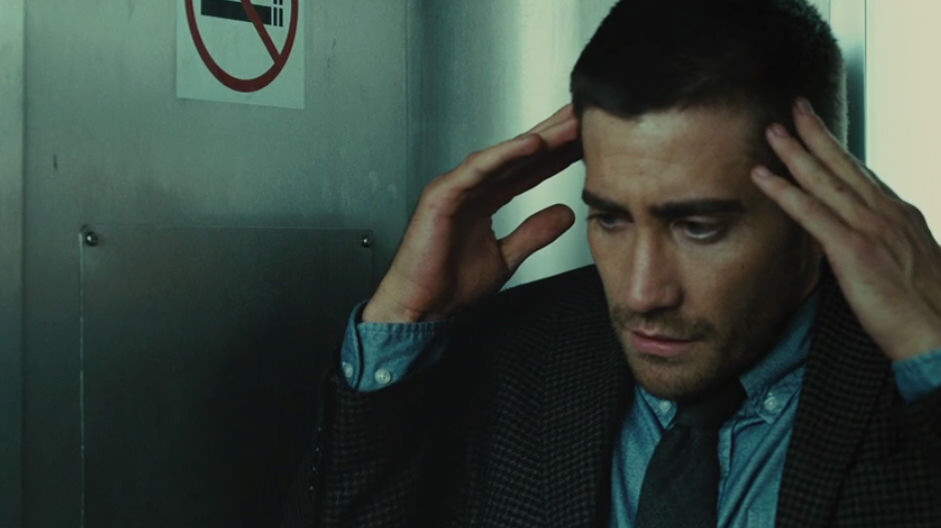 Source-Code Jake Gyllenhaal in train bathroom clutching his head in thought
