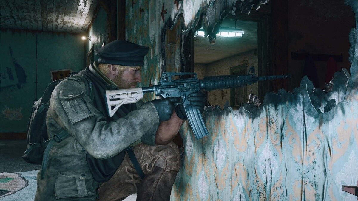 Rifleman points gun through large hole blown in wall.