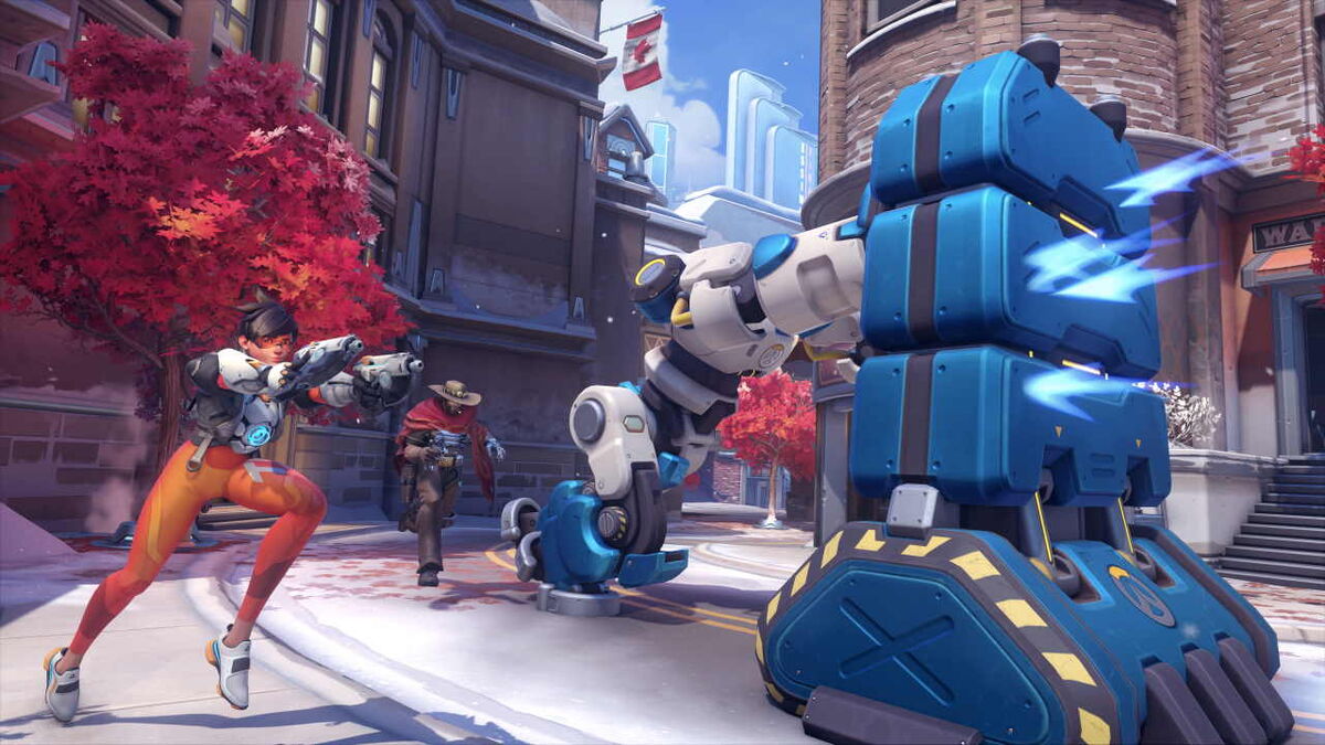 A large robot pushes a heavy item down the road while Tracer and McCree guard.