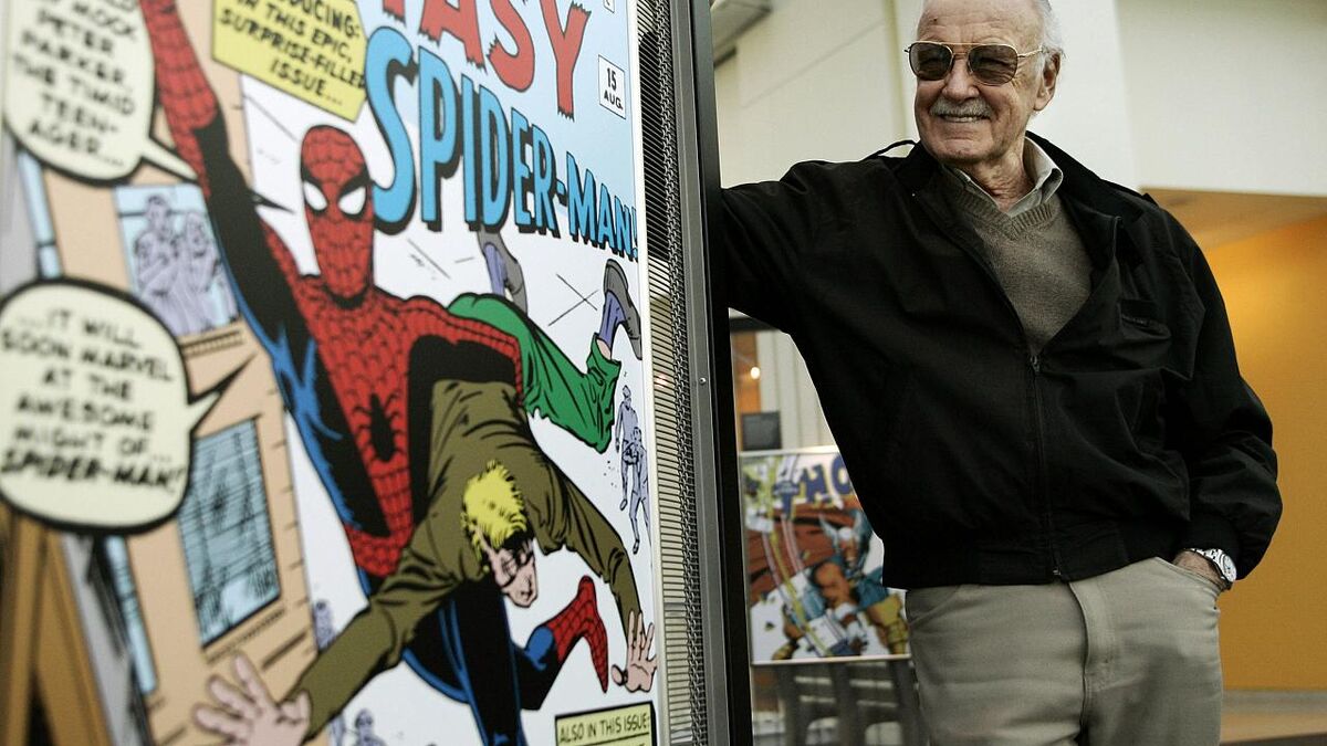 Stan Lee stands next to a Spider-Man bus stop ad