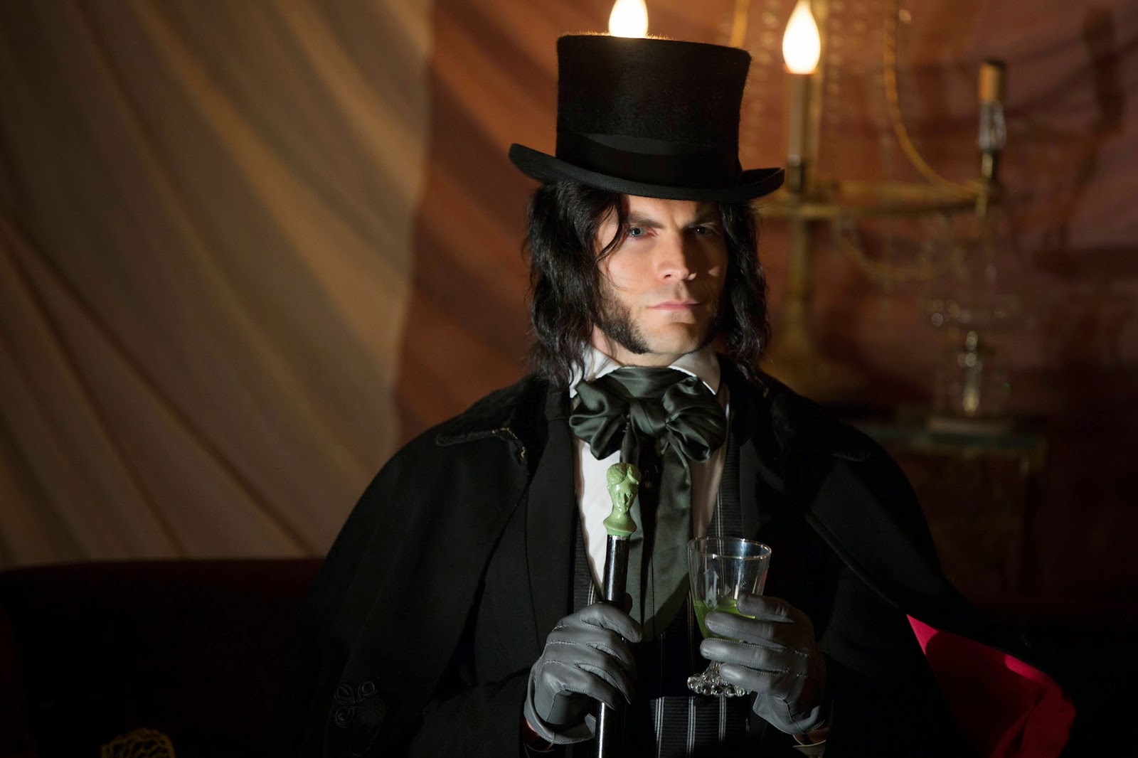  Edward Mordrake, a character from American Horror Story, is pictured with a top hat, cane, and glass in hand staring off to the side.