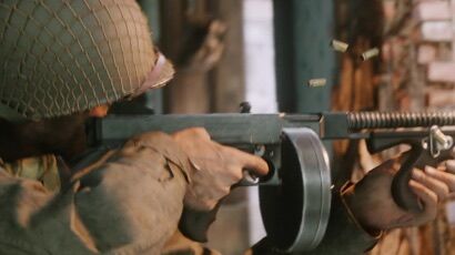 A man holds a gun, which happened often in World War II.