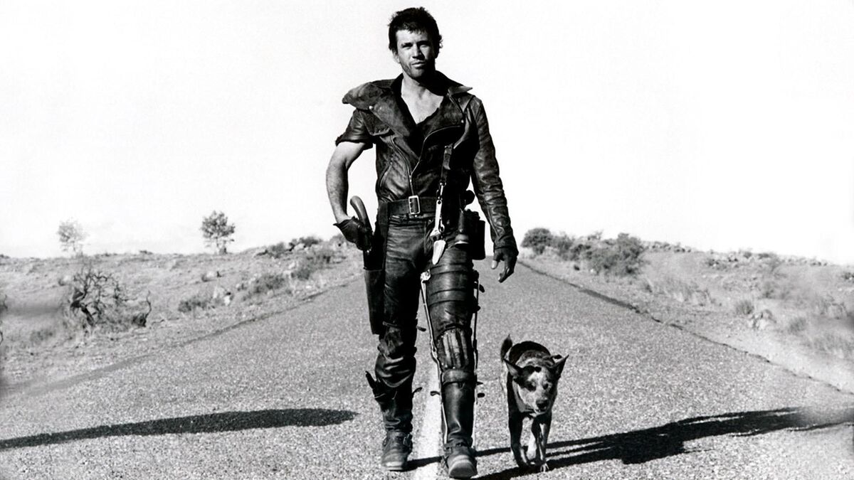 Mel Gibson in Mad Max walking along a road with a dog by his side in the outback