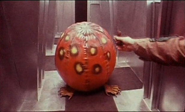 dark-star inflatable red-spotted alien in an elevator being tickled