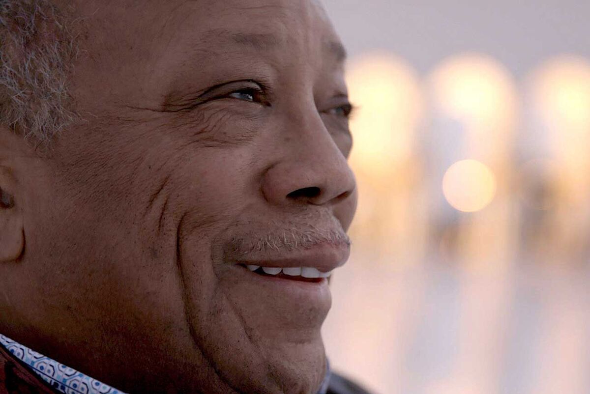 Quincy Jones smiles while looking off camera.