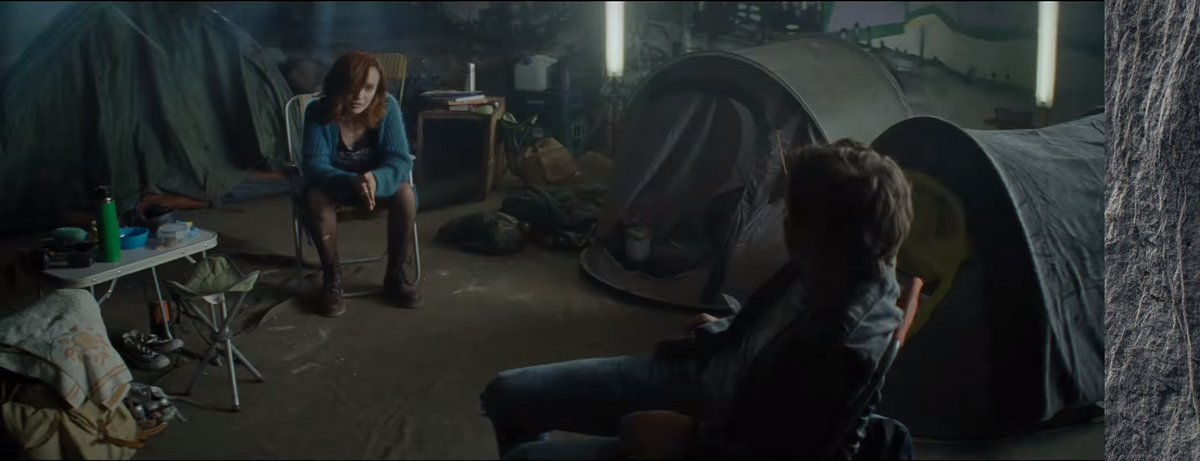 A scene from one of the trailers, with Samantha and Wade sitting in a dark room, filled with tents.