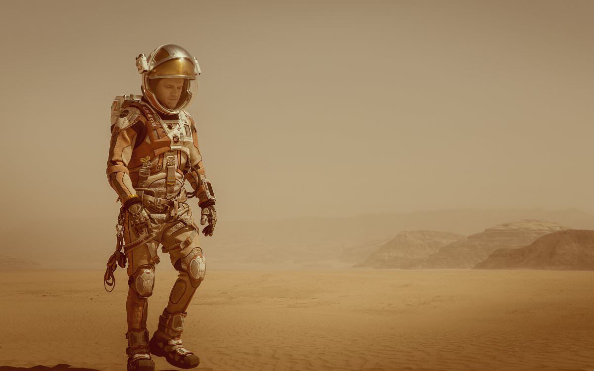 the martian matt damon in space suit walking across Mars sand