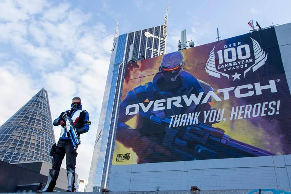 Tim Nicholas as Soldier 76, standing triumphantly before promotional billboard.