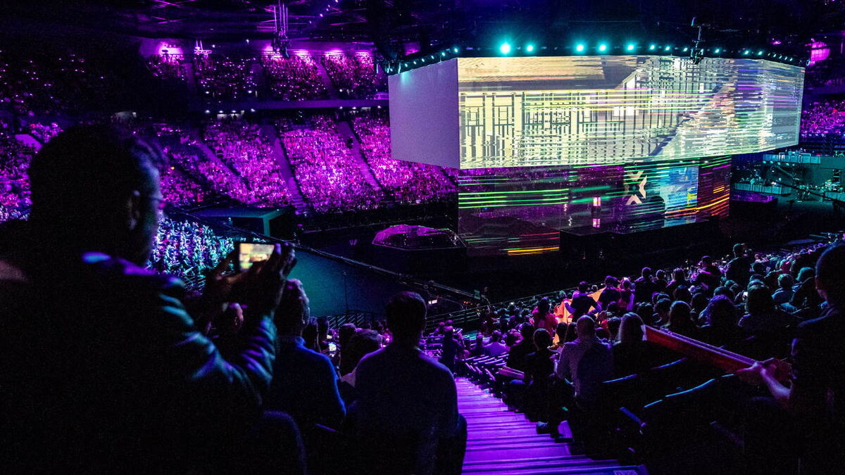 A crowd full of people hold their phones up to the stage.