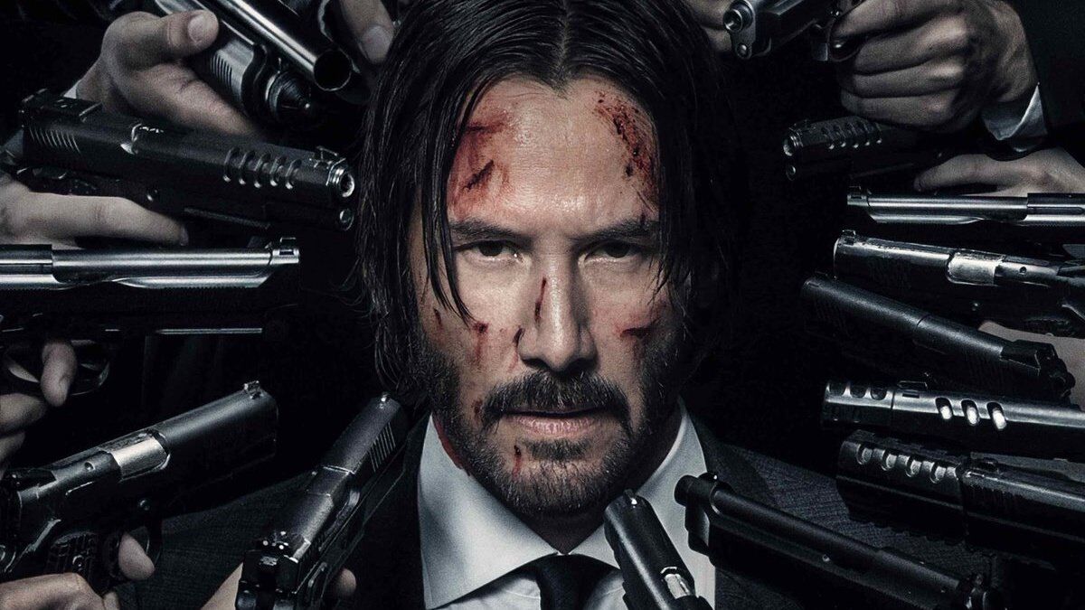john wick keanu reeves with lots of people pointing guns at his head