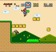 This screenshot shows Mario riding Yoshi during the first level of the game. The scenery shows a jungle environment with floating blocks scattered in the air. The interface displayed around the corners shows the number of lives the player has, the Dragon Coins collected, the player's stored power-up, the level's remaining time, the player's number of coins, and the total score of the player.